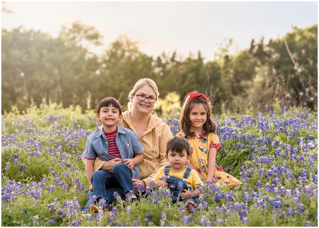 mom in yellow sitting with her 3 kids in a lavender field