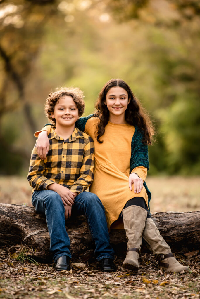 siblings smiling while sitting on a tree waco pediatric dentist