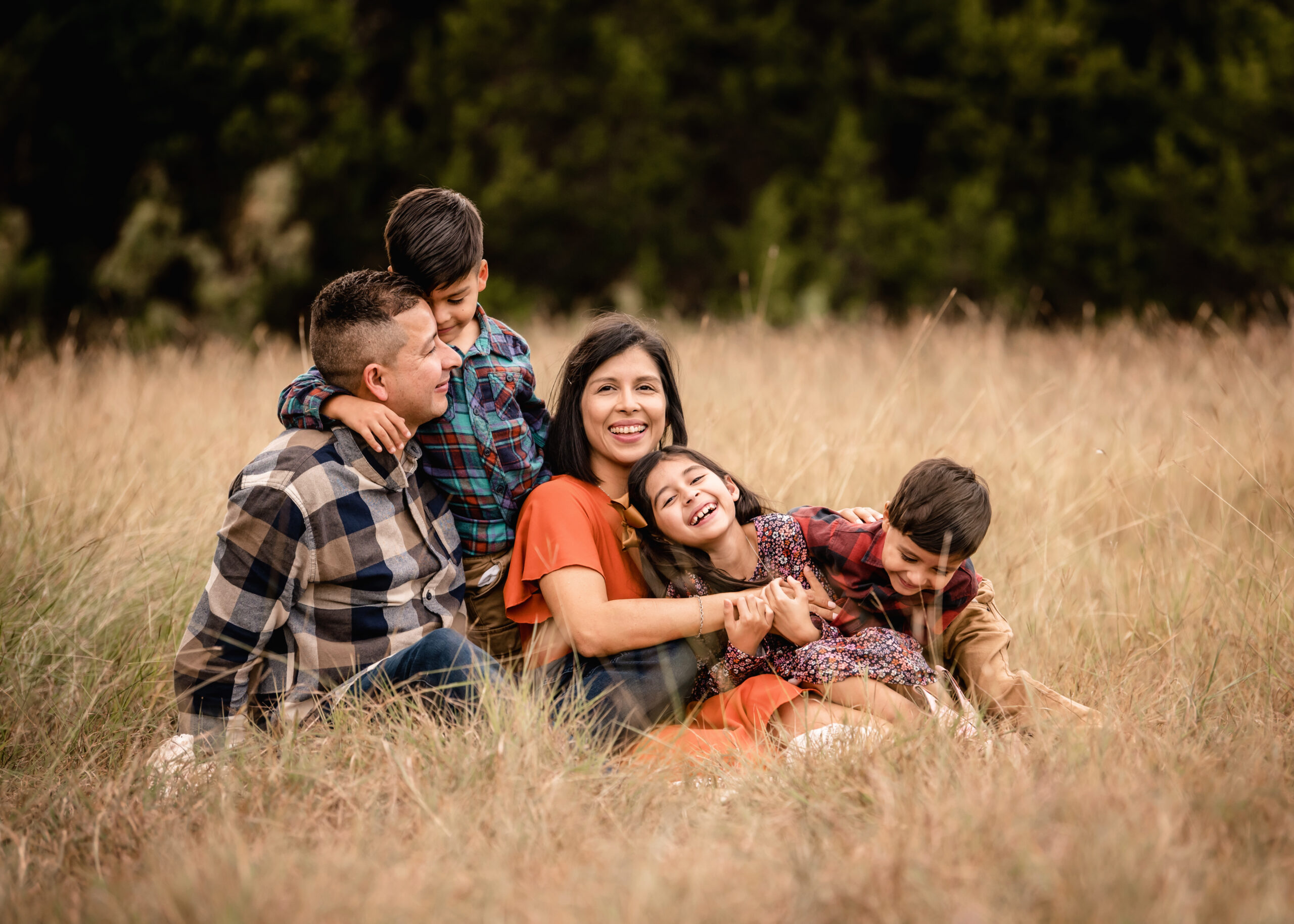 family of 5 laughing and playing in a field