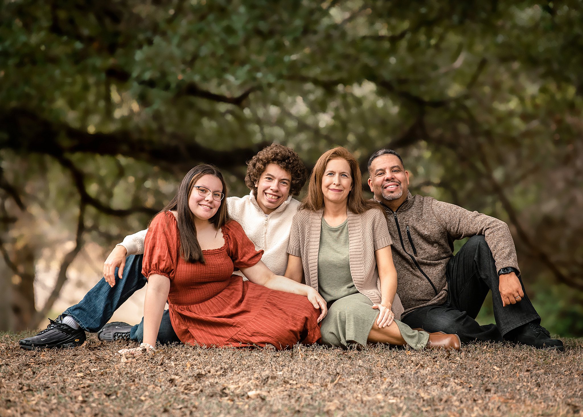 family sits together amongst the forest