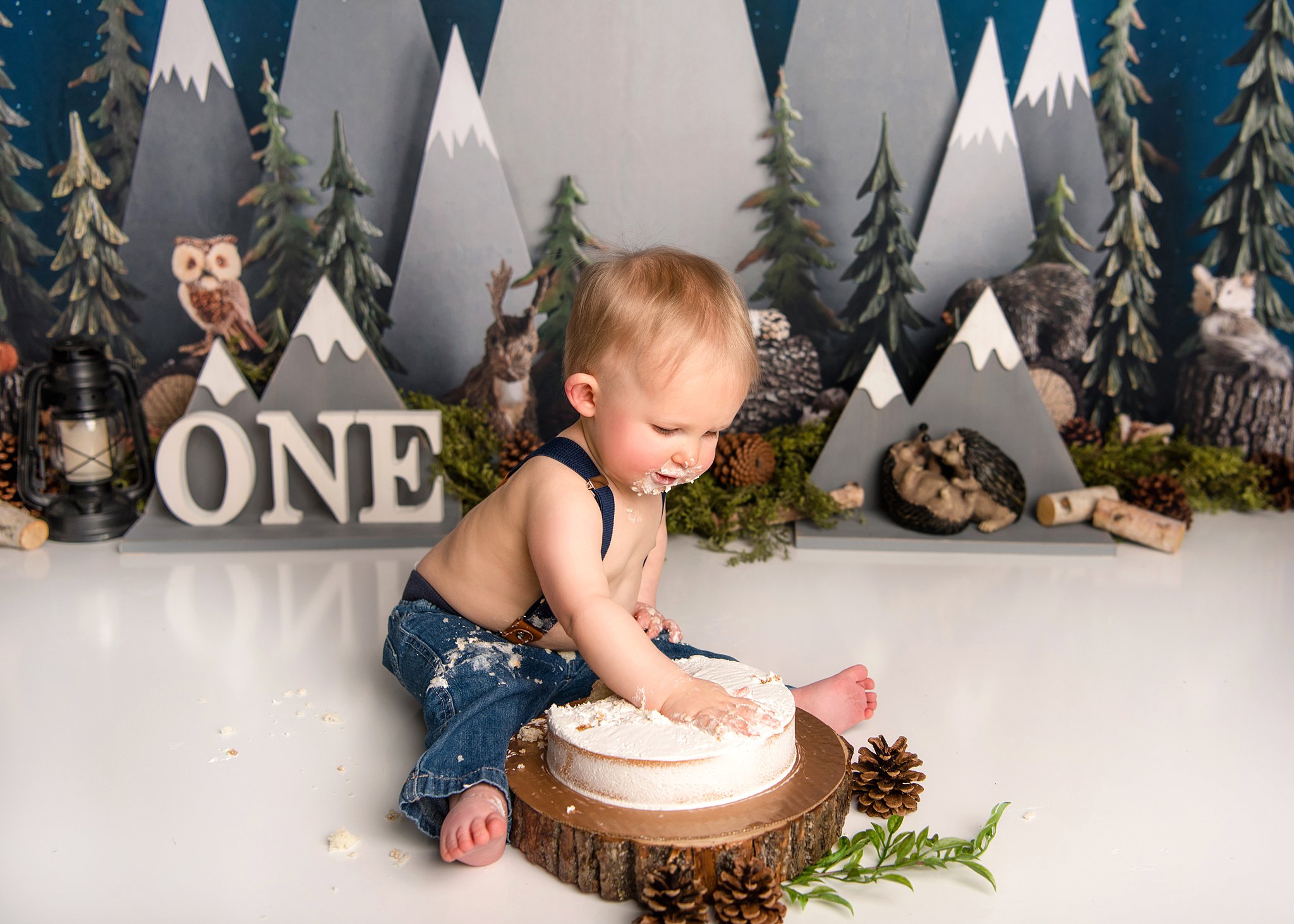 A toddler wearing blue denim overalls smashes his birthday cake in a mountain scene things to do in waco tx with toddlers