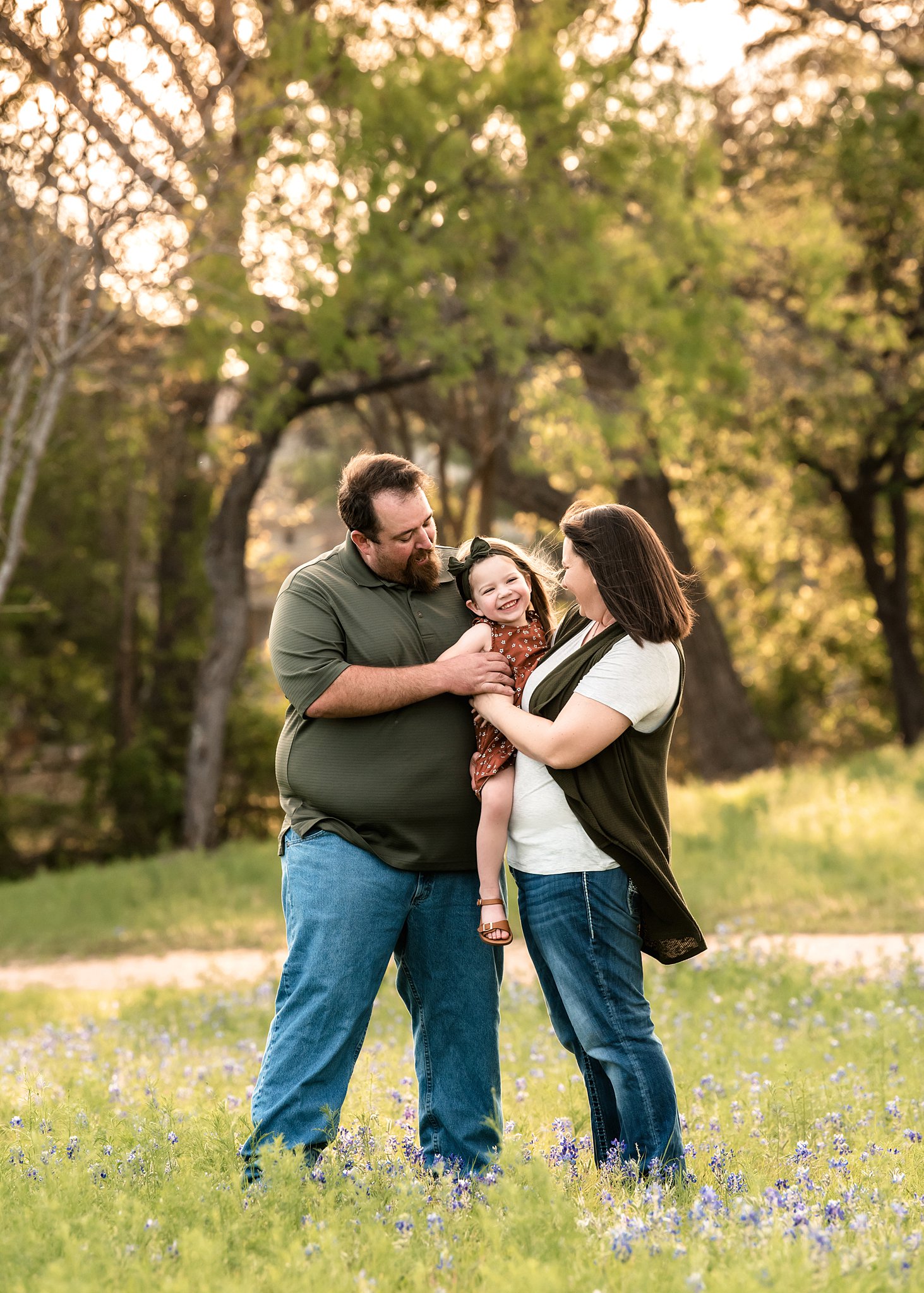A mother and father hold their toddler daughter and play and tickle her spas in waco
