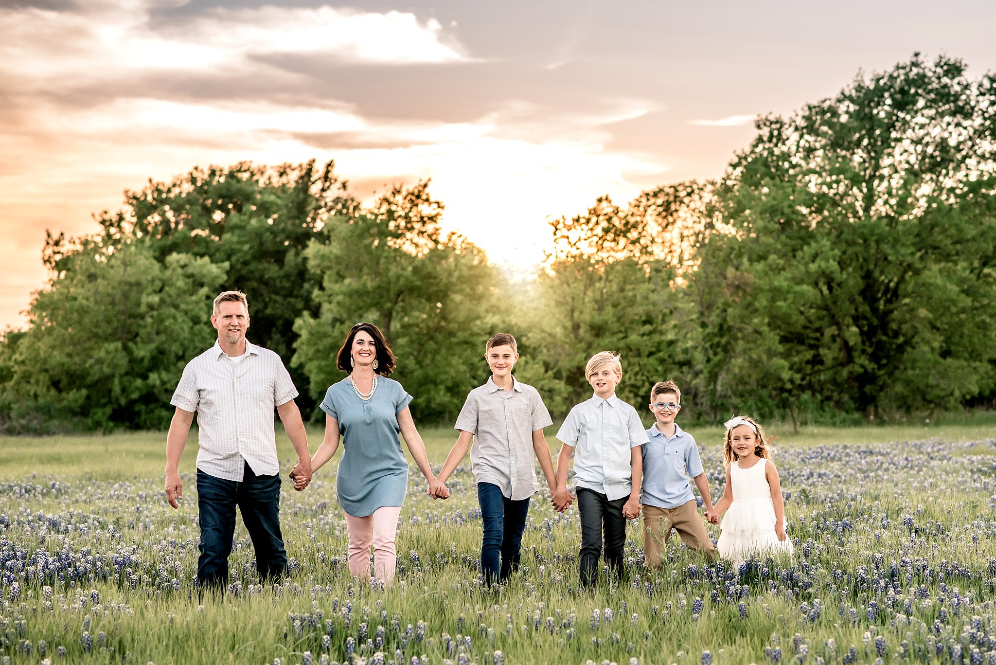 A family of six walks through a field of wildflowers holding hands at sunset waco restaurants with playgrounds