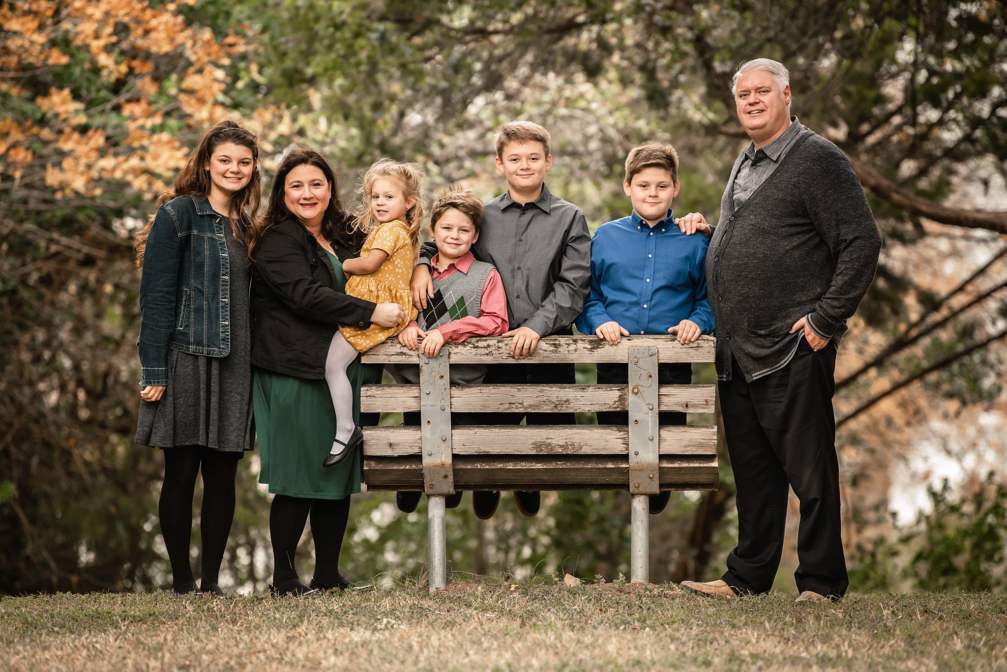 A large family of seven stands around a park bench together waco restaurants with playgrounds